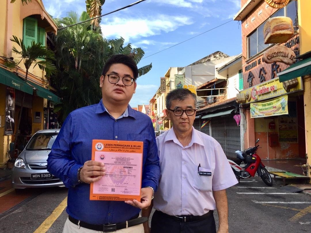 沈荣森（左起）与陈劲源 齐展示市政厅，批准由甲 州姑务乡村社区管理理事 会接管海山街跳蚤市场的 执照。