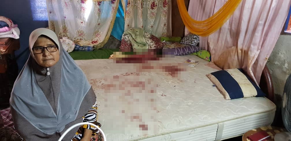 死者祖母惹米拉(60岁)坐在案发的床上，床褥血迹班班。