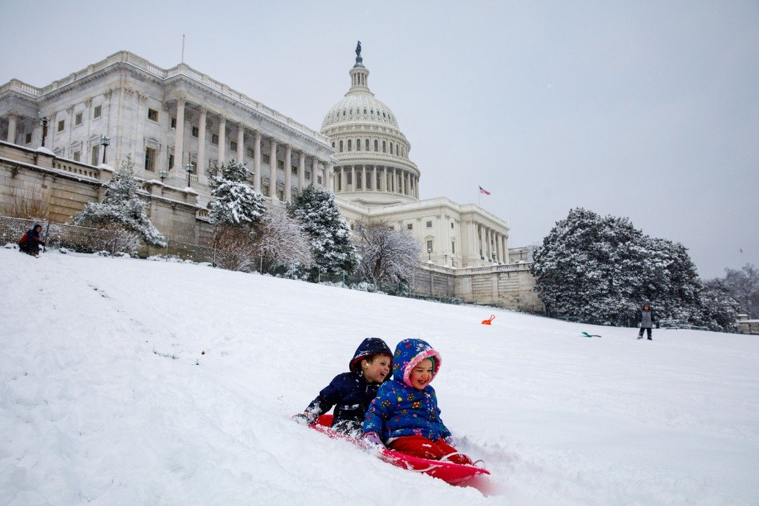 美国中西部上周末遭冬季暴风雪席卷，造成交通瘫痪及多起伤亡事故，暴风雪料将吹向大西洋中部地区。图为两名幼童在国会大厦一旁厚实的积雪中玩乐。