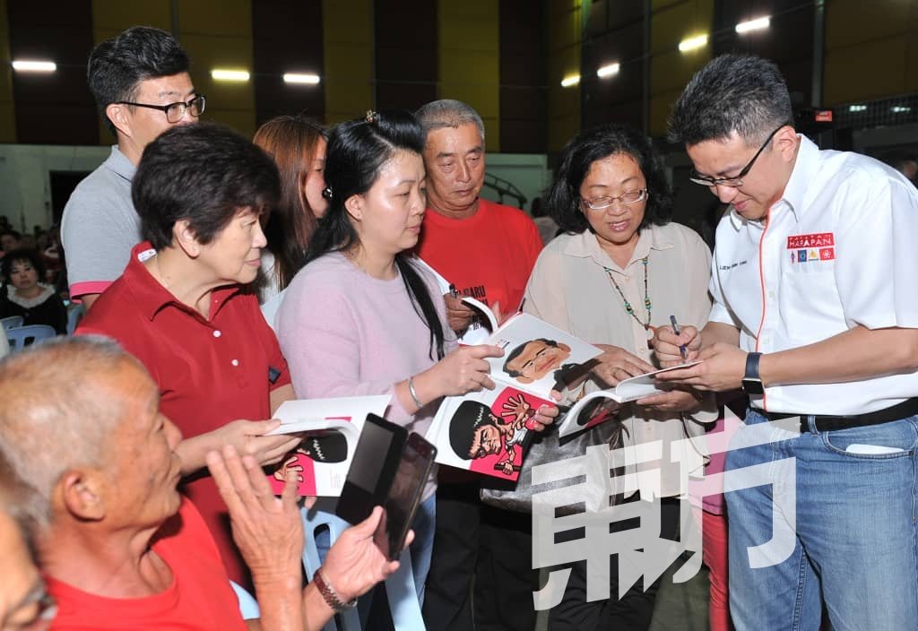 支持者现场购买«face面子»书籍后，向刘镇东（右）及其他行动党领袖索取签名。 （摄影：连国强）