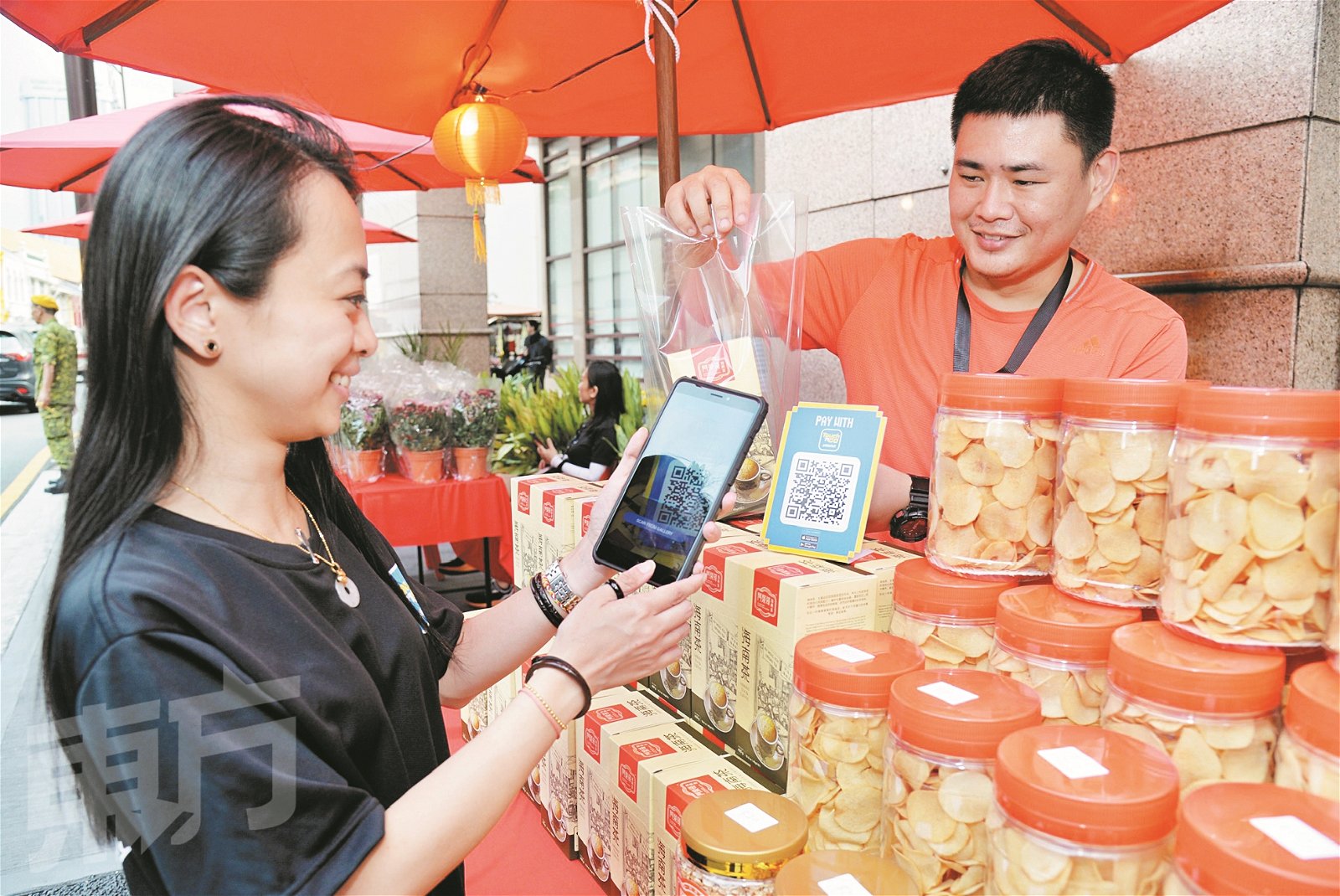 年味节市集与时并进推广无现金交易，让民众轻轻松松通过手机转帐就可购买年饼。