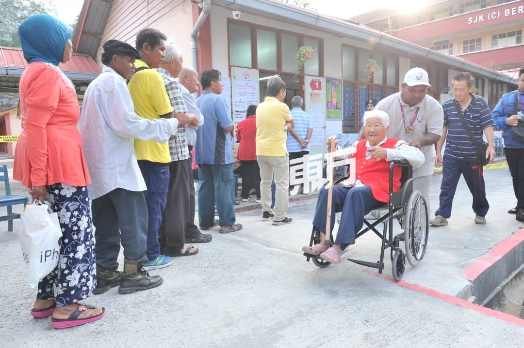 93岁老选民李爱行动不便，选委会工作人员用轮椅推进投票中心投票，并在上午8时许完成投票。
