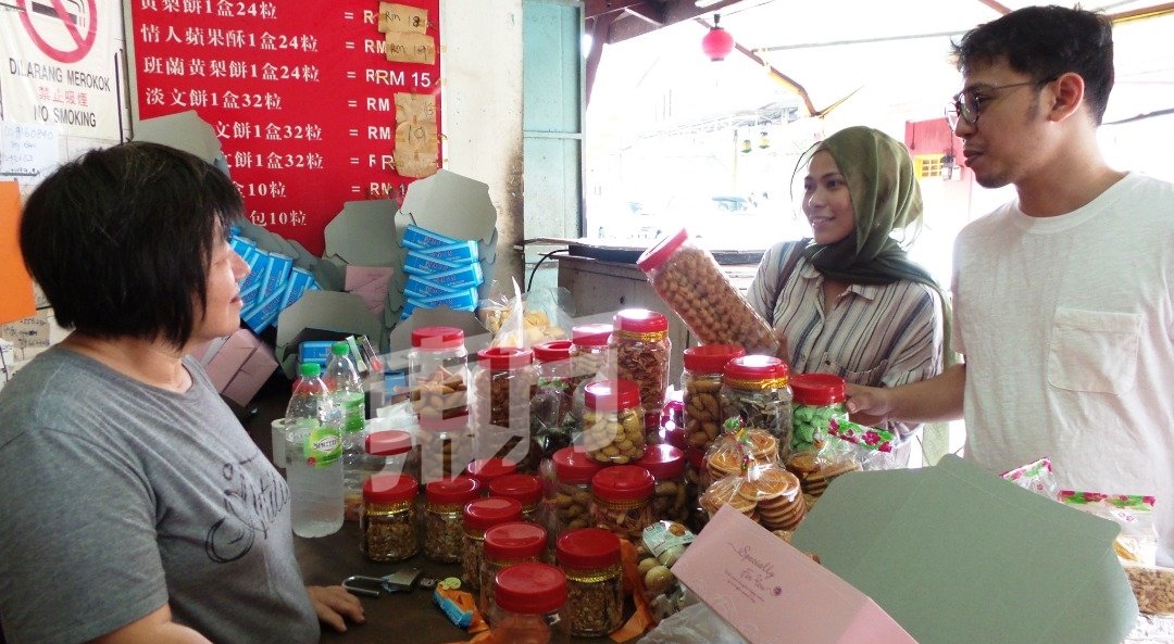 年轻马来同胞来到马六甲鸡场街，看见多样款式的农历新年年饼也停下脚步选购。 （摄影：黄毓萍）