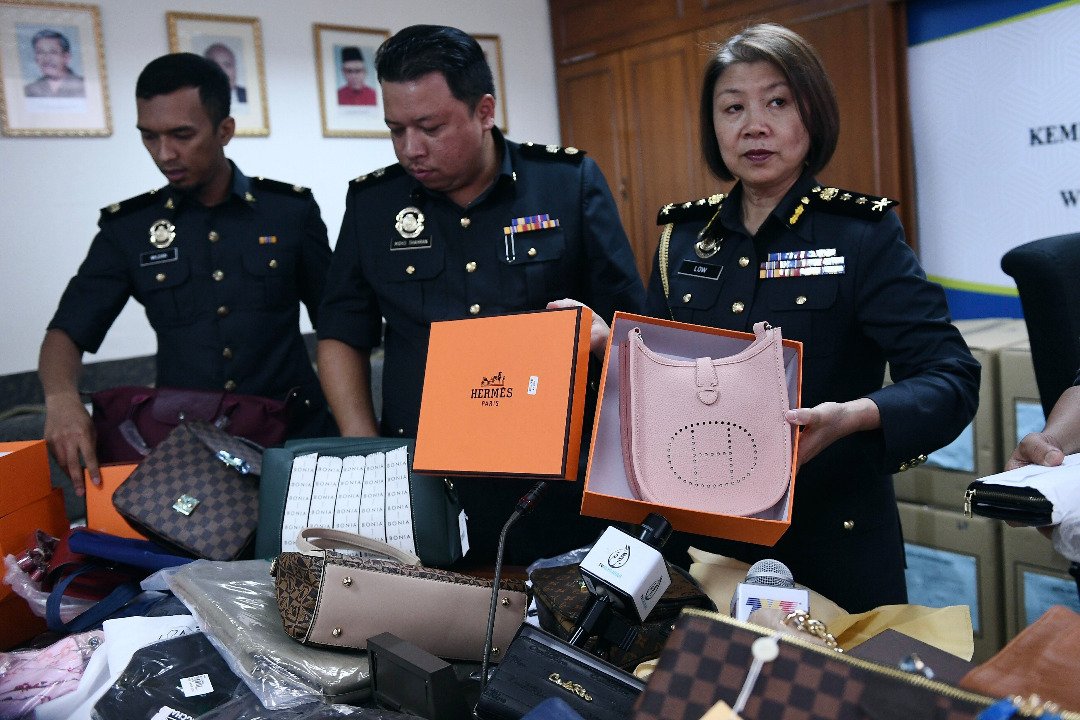 刘雪虹（右）向媒体展示起获总值逾50万令吉的赝品名牌手提包和皮包。