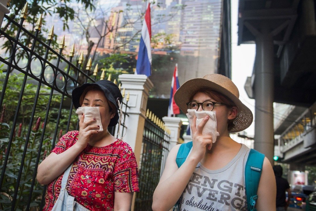 曼谷空气污染严重，两名女子走在曼谷市中心时，用纸巾摀住鼻子。