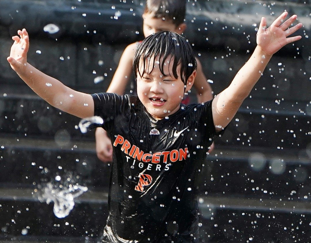 酷暑气候下，一名孩童在纽约曼哈顿华盛顿广场公园的喷水池中玩水消暑。热浪近日侵袭美国多个地区，该国人口最多的纽约市，自上周五起就已经处于高温状态。