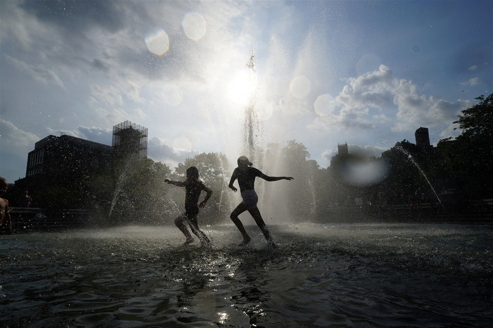 华盛顿广场上，孩童在喷水池中戏水，为这炎热的季节里带来一丝清凉。气象部门估计，来临的周一起，中西部及东部地区的高温将会有所减退，甚至低于以往的平均水平。