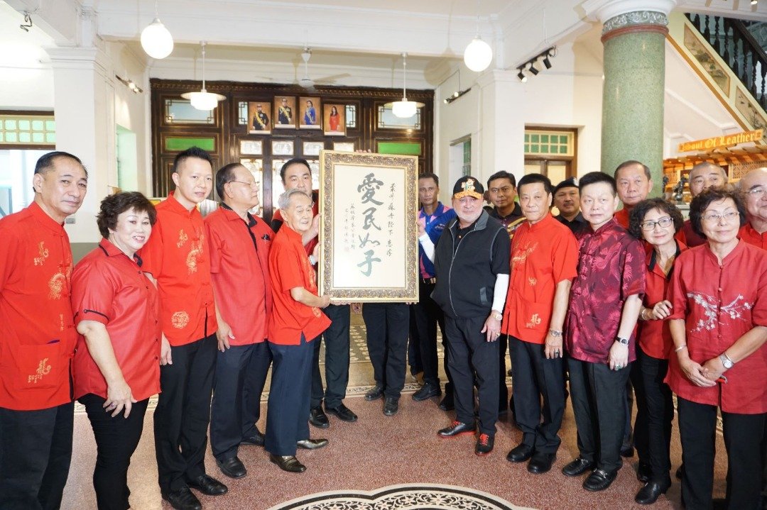 黄国华（左5起）率领众麻坡漳泉公会理事赠字书给依布拉欣陛下。