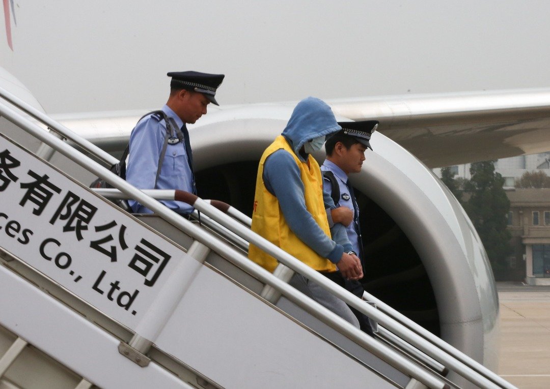 一名被移交中国当局审理的台湾诈骗嫌犯，由警员押解走下飞机。周五抵达北京的诈骗案嫌犯，是3年前捣破的诈骗案中，最新一批引渡到中国的涉案者，94人全部来自台湾。至今，西班牙已分批押解218名涉案台湾嫌犯到中国。