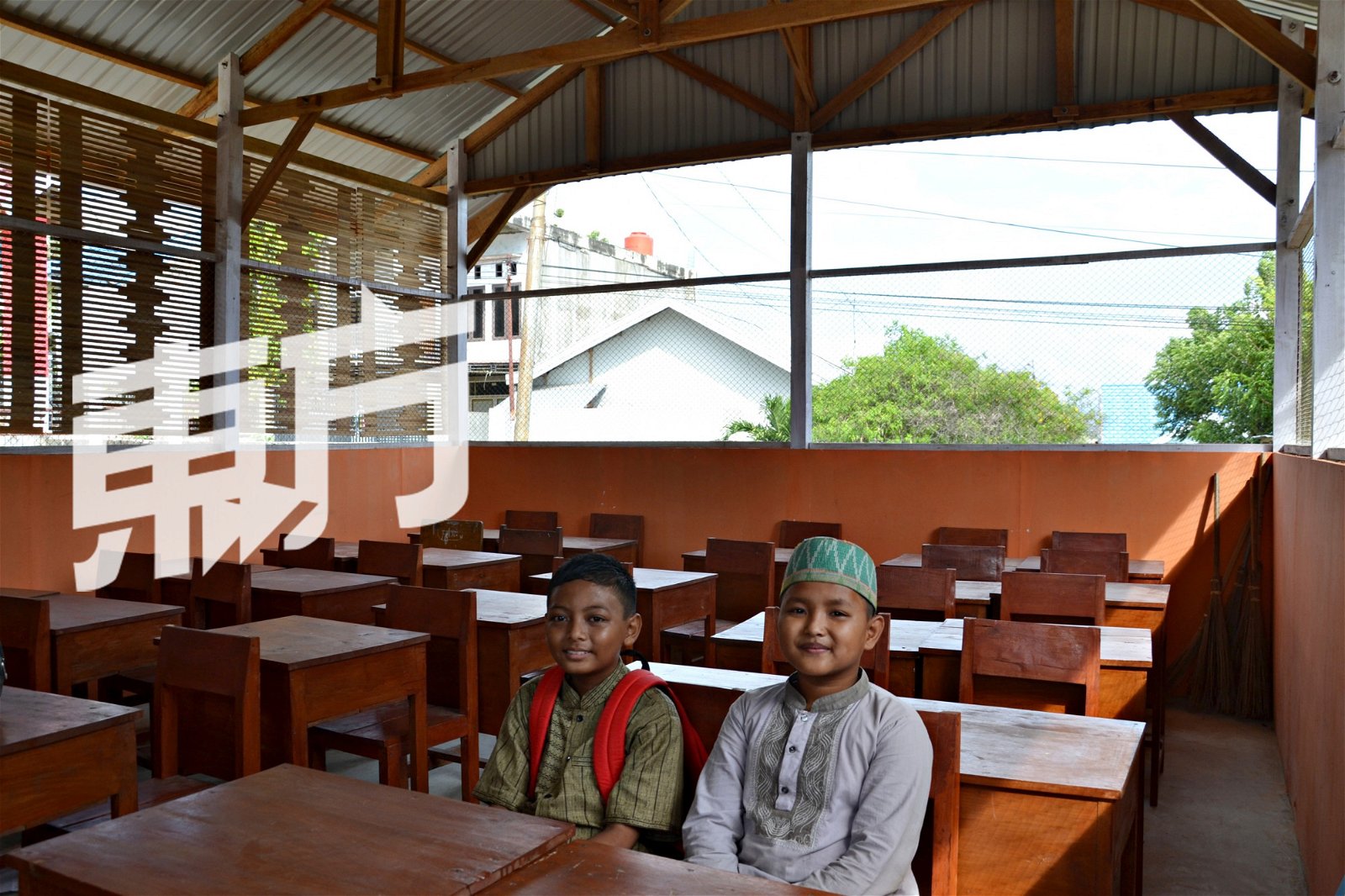 10岁的嘉迪杜尔（Jatidul Iman Aulia，左）和莫阿里夫（Muh Alif Sudarwanto）开心地坐在WVI援建的临时课室里。对他们而言，能够回校上课，意味著很快就能回到生活的正轨。