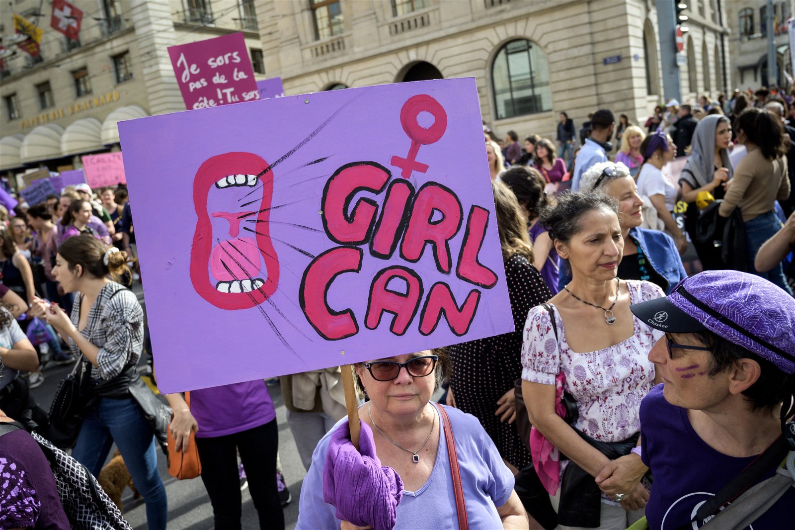 一名妇女报手举海报参与日内瓦的示威活动，为遭受不平等对待的广大女性发声。