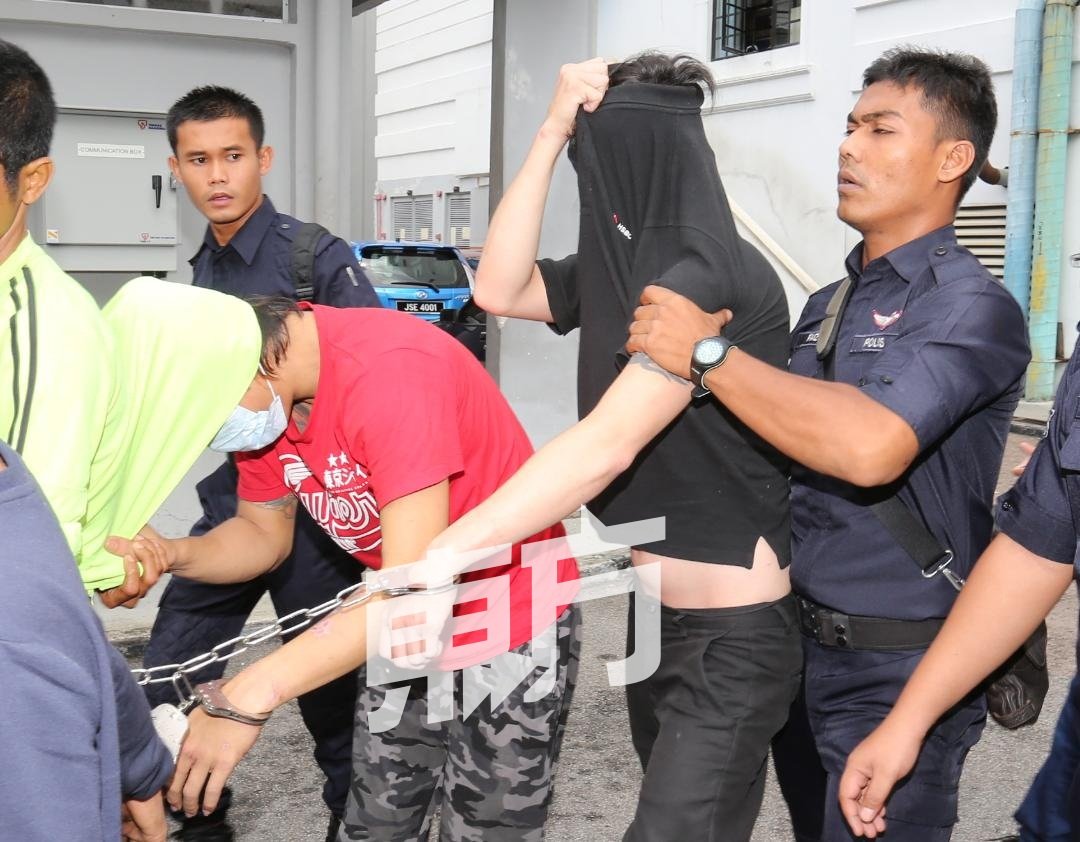 两名嫌犯周一被带至新山推事庭申请延扣时，以衣遮脸。（摄影：刘维杰）