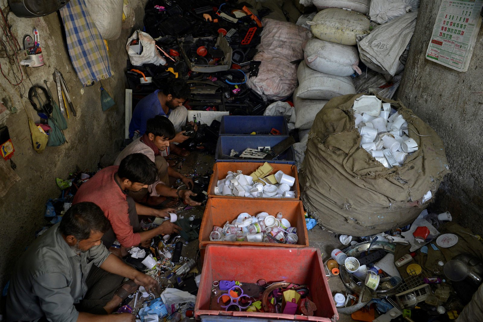 几名印度工人在达拉维平民窟中的一家工作坊，将塑料一一分类。据估，约有5000家企业在达拉维的1万5000间工作坊中营运，当中的产业包括陶器、皮革和纺织等。
