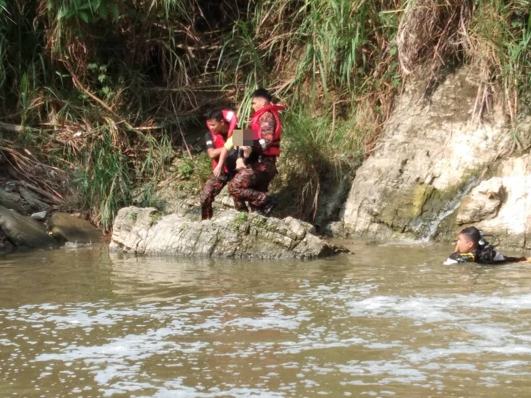 消拯人员合力将从河底搜获的少年尸体抱上岸。