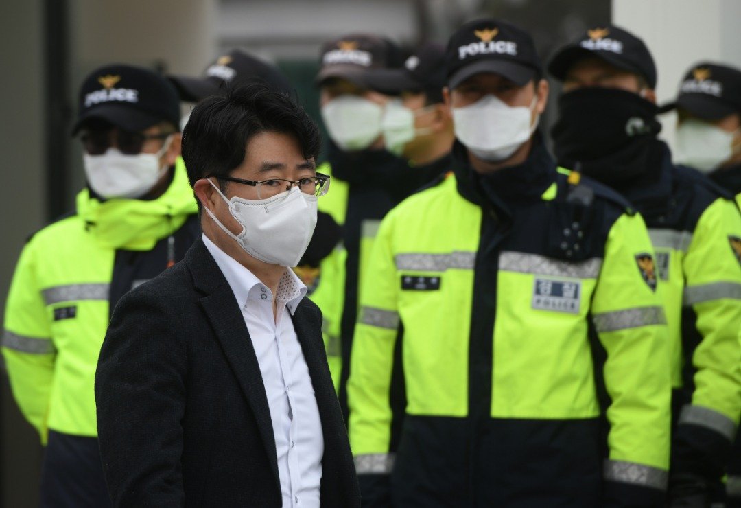 受到高浓度的悬浮粒子影响，韩国当局呼吁民众不要进行户外活动，外出的时候需佩戴口罩。这是一名戴著口罩的韩国男子，经过一群在政府大楼外驻守的警员。