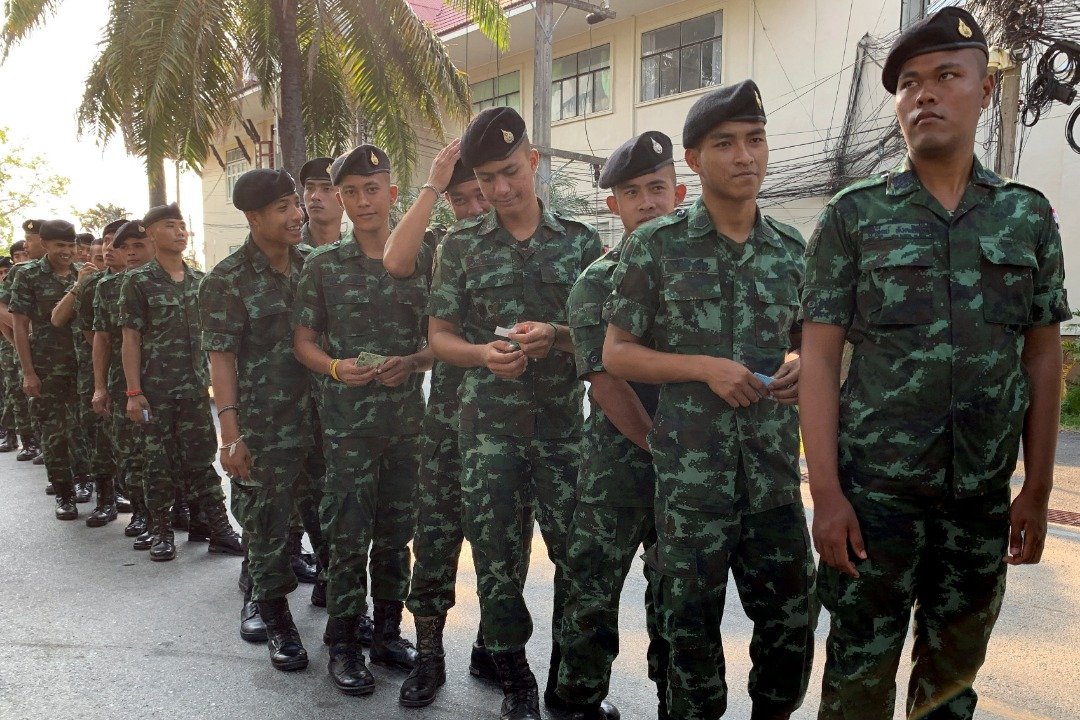 泰国士兵们周日在北大年府其中一处投票站有秩序地排队，等候投票。此次选举亦是自2014年泰国军事政变以来的首次选举，据报，现任首相巴育的军方背景已令其稳操250张“军人票”。