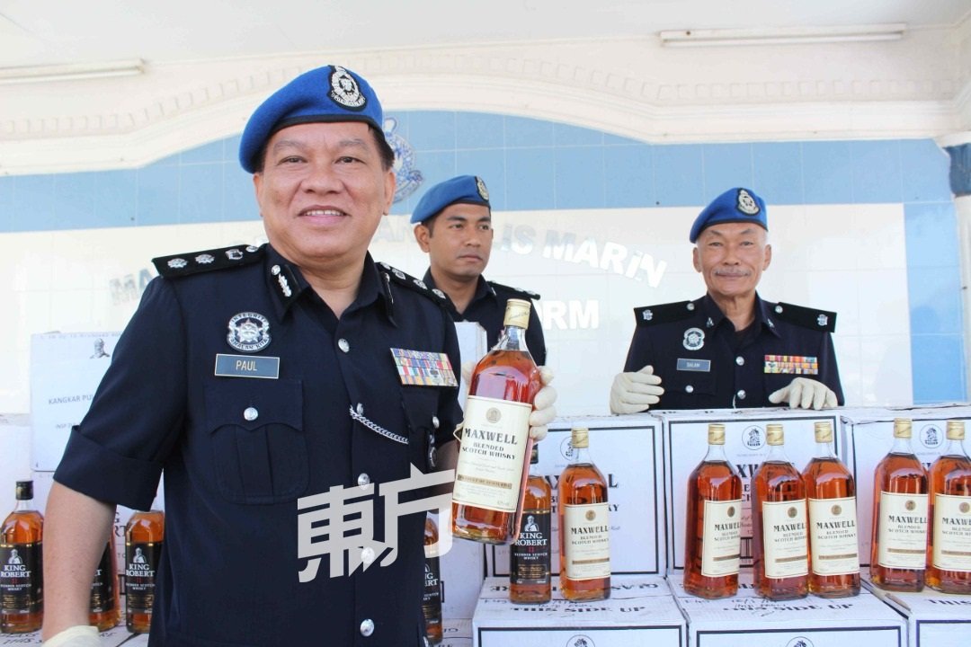 丘保罗（左）展示水警起获的走私酒，总值47万0400令吉。