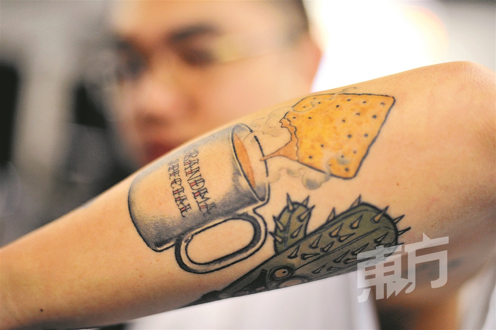 “咸饼沾美禄”是很多人的童年回忆，何佳玮将这段与阿嬷的回忆纹在手臂上。（摄影：蔡开国）