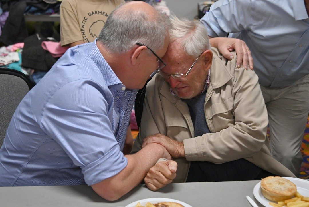 澳洲总理莫里森（左）周日到新南威尔士州的灾区探望灾民，家园被烧毁的85岁灾民华兰忍不住落泪，莫里森伸手环抱安慰他。