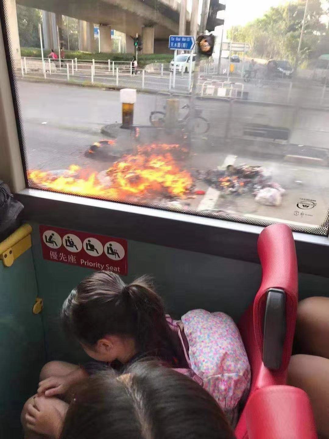 巴士驶过被示威者纵火的路口时，有学童被吓得低头不敢往外看。