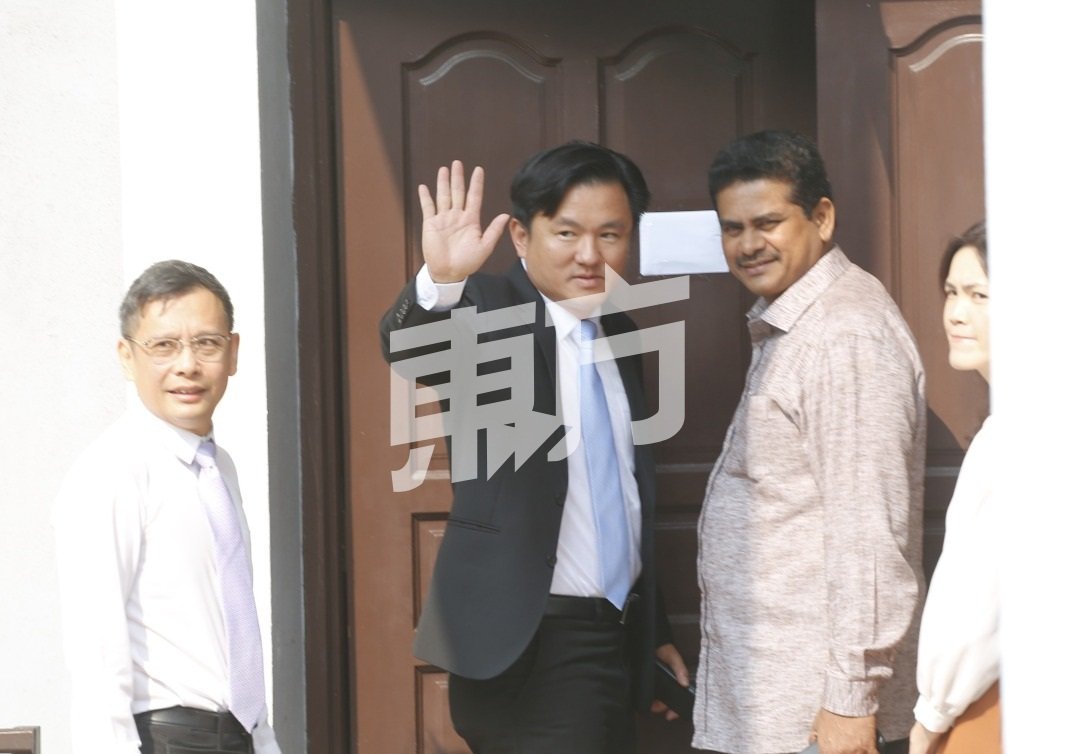 杨祖强（左2）在步入法庭前，转过身向在被拒于法庭外的支持者挥手示意。左起廖泰义、西华苏巴玛廉。