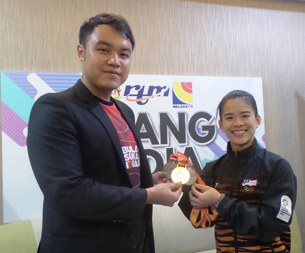 陈昌敏（右）向郭子毅出示在世界武术锦标赛夺下的金牌。