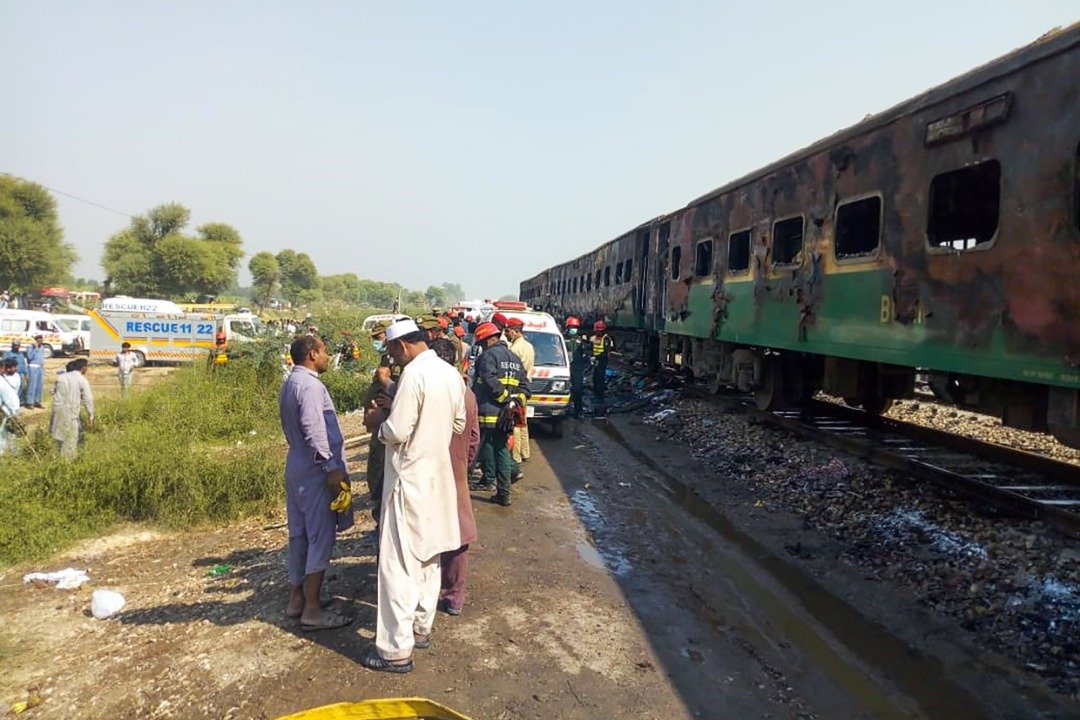 救援人员站在烧毁的列车车厢旁边，随著救援工作深入，当局相信罹难者人数会继续攀升。