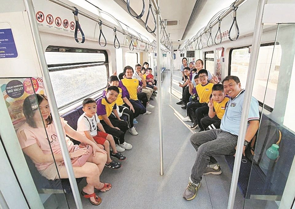 郭镇坤（右）与其他老师一起带孩子们乘搭电动火车，到吉隆坡进行户外教学。
