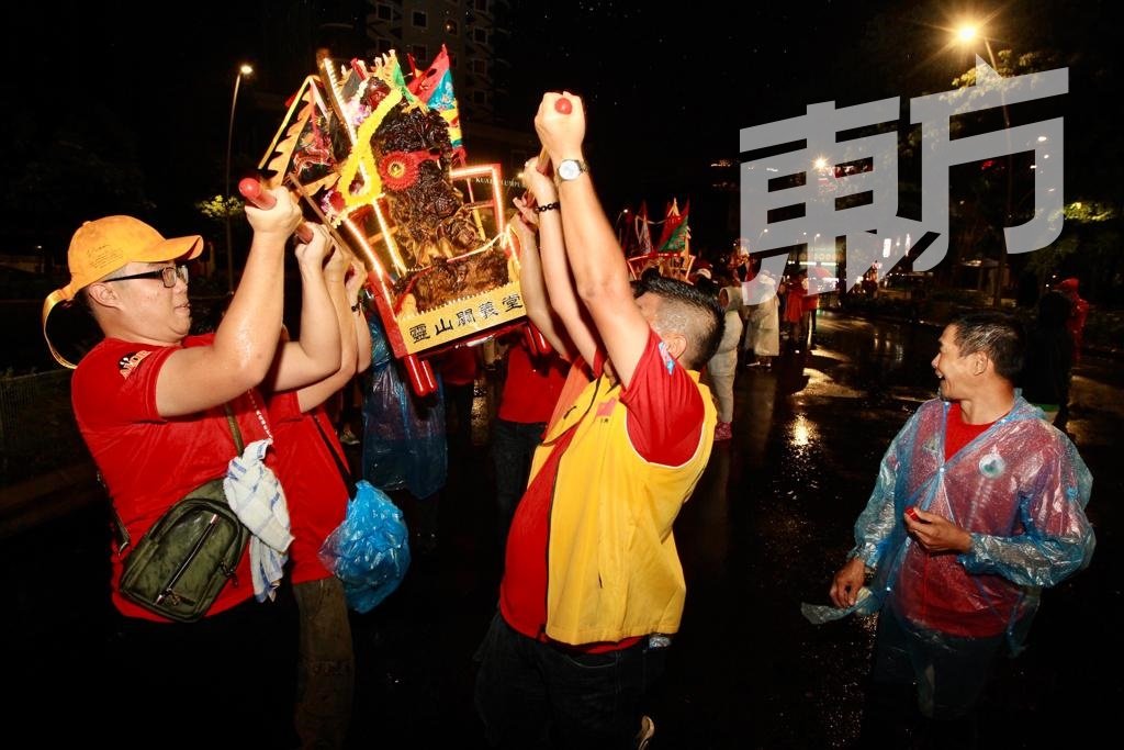 即使天降大雨，但2019年“马来西亚国际关公文化节”茨厂街恭迎站出巡夜游依旧照常进行，游行者不被雨水破坏了心情，反而越发起劲摇晃鸾轿。（摄影：甘月仙）
