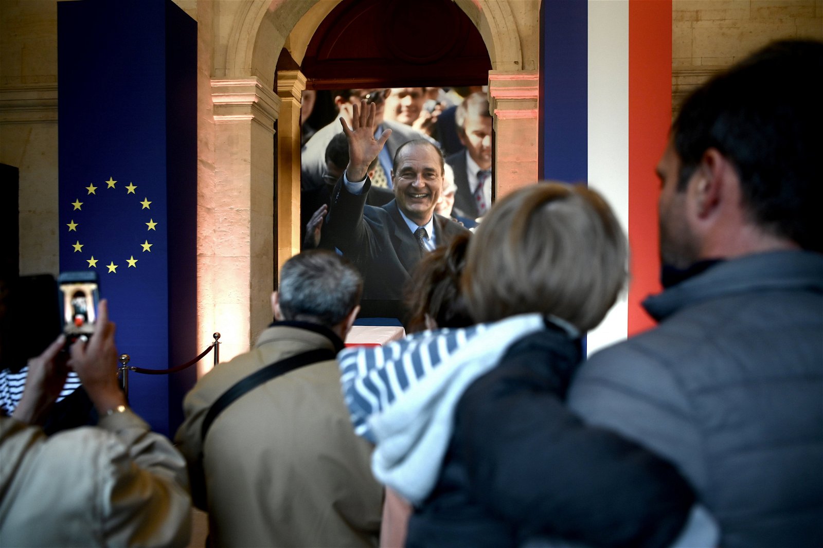 法国前总统希拉克向人们挥手微笑的大幅照片，悬挂在灵柩上方，灵柩两侧亦放置著欧盟旗帜以及法国国旗。有前来瞻仰遗容的民众，朝著希拉克的照片拍照留念。