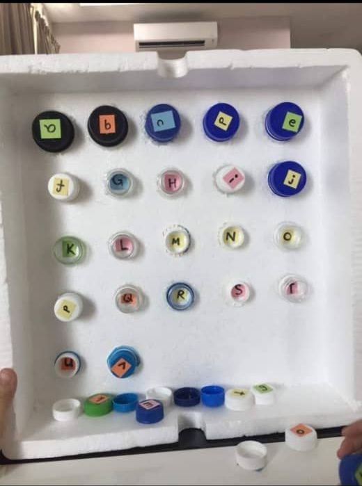 用塑料瓶口及瓶盖制成的英文大小字母游戏板，可让孩子边玩边学习。
