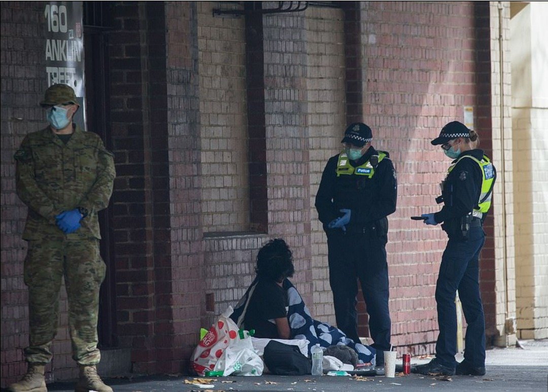 戴著口罩的澳洲军警人员周四，正对一名露宿于墨尔本街头的流浪者进行盘问。