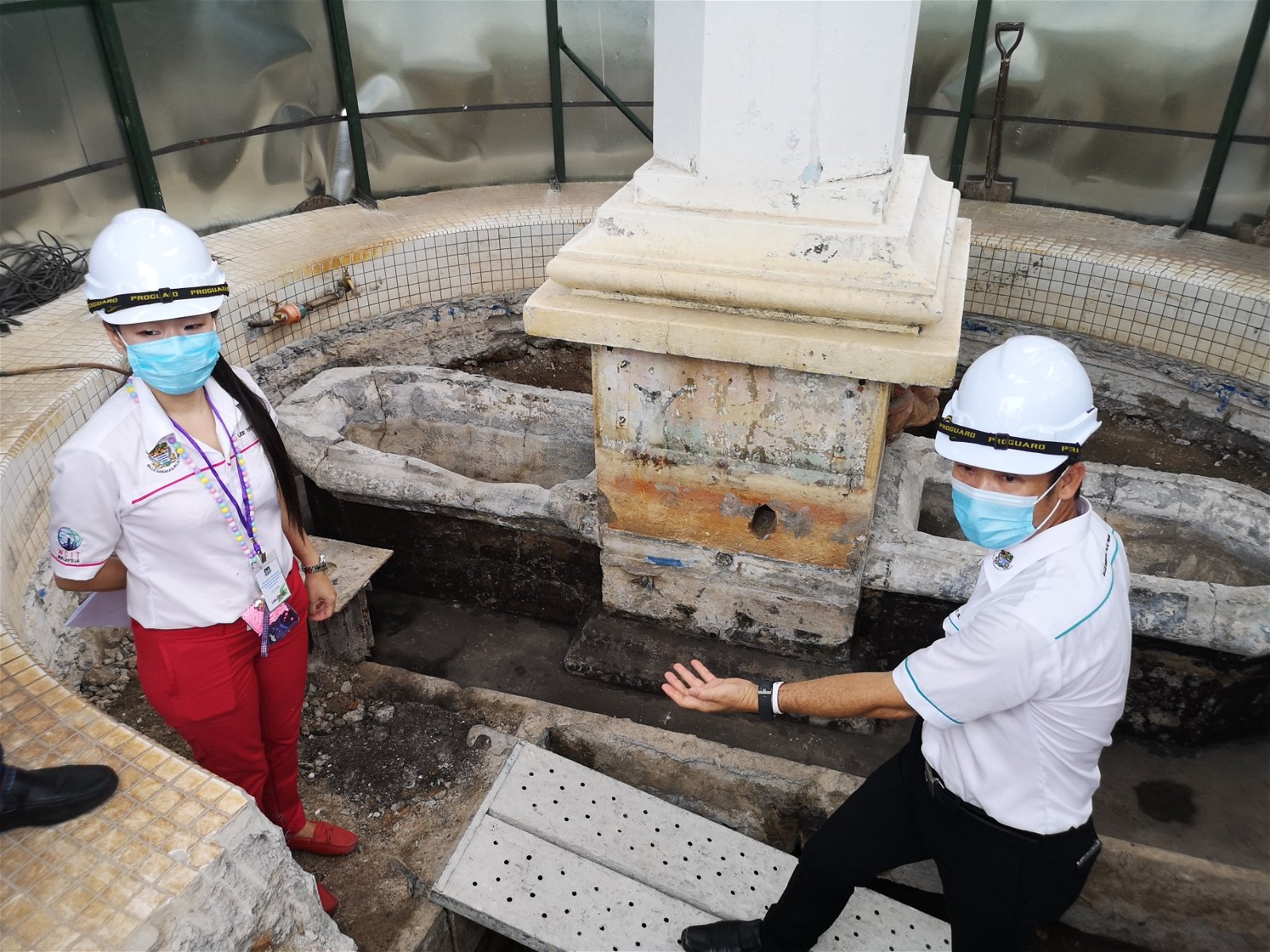 尤端祥（右）与槟岛市政厅工程师巡视，纪念碑地下的水槽原貌。