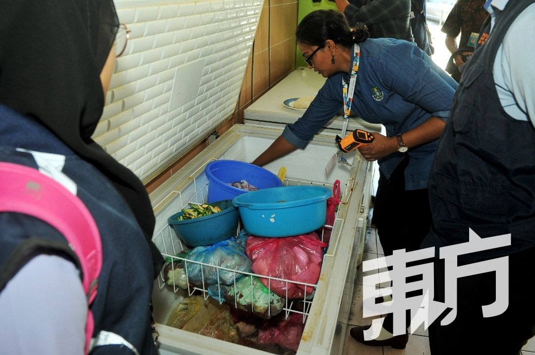 官员仔细检查食店的冰箱，确保业者贯彻正确的食物储藏方式，以确保食材的新鲜及不受污染。（摄影：蔡开国）