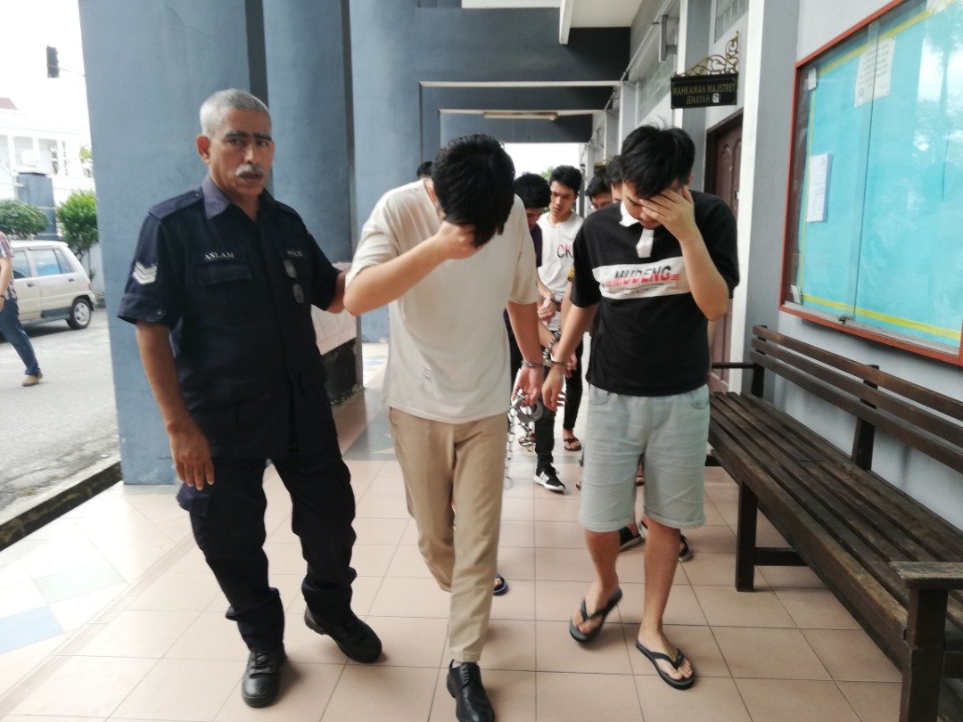 首批8名中国籍男子被押往怡保第二推事法庭面控后，纷纷低头避开镜头。