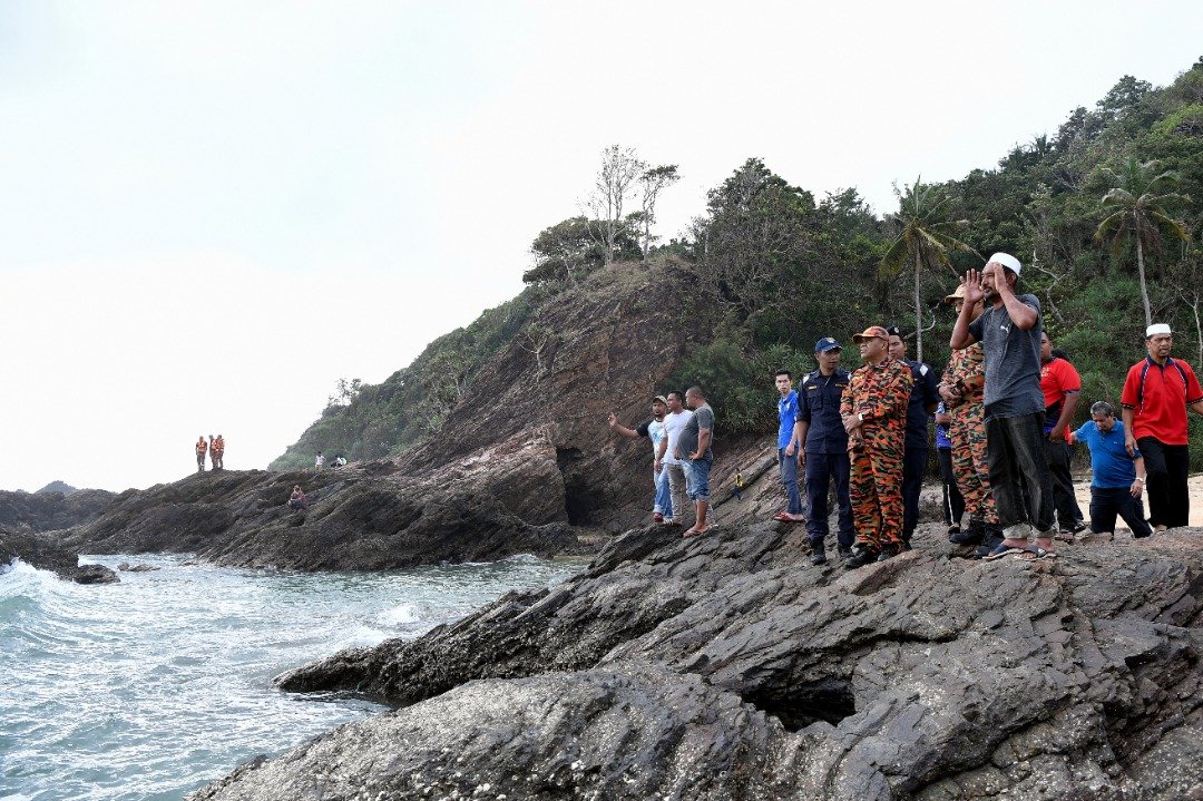 祖基拉萨（前排右）在海边祈祷，希望早日寻获儿子的踪影。