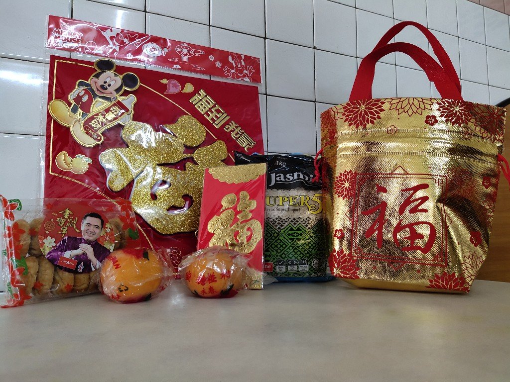 陆兆福带著拥有一包一公斤白米、一包饼、红包袋、福字装饰及2粒年柑的福袋，向知知港市民提早拜年。