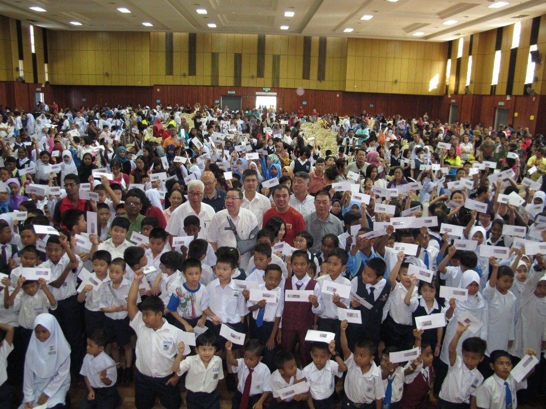林冠英（中）与峇眼区受惠的中小学清寒学生合照，每名学生可获100令吉援助金。