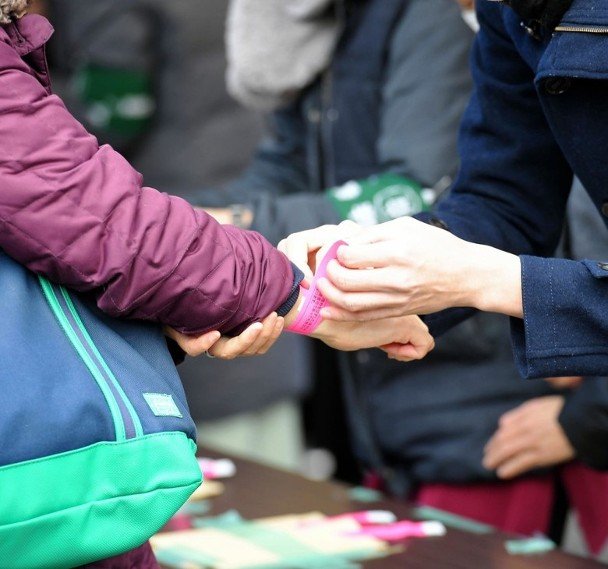 工作人员为排队市民扣上粉红色的抽签手带。