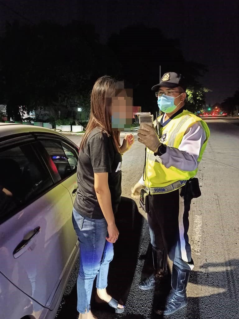 警方在设路障检查行动中，测试驾驶人士是否有酒驾。