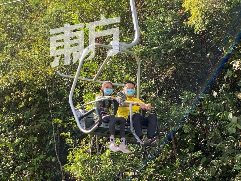 杨顺兴（右）携带女儿体验世外逃园的空中吊缆，穿越在自然环境的树林之间。