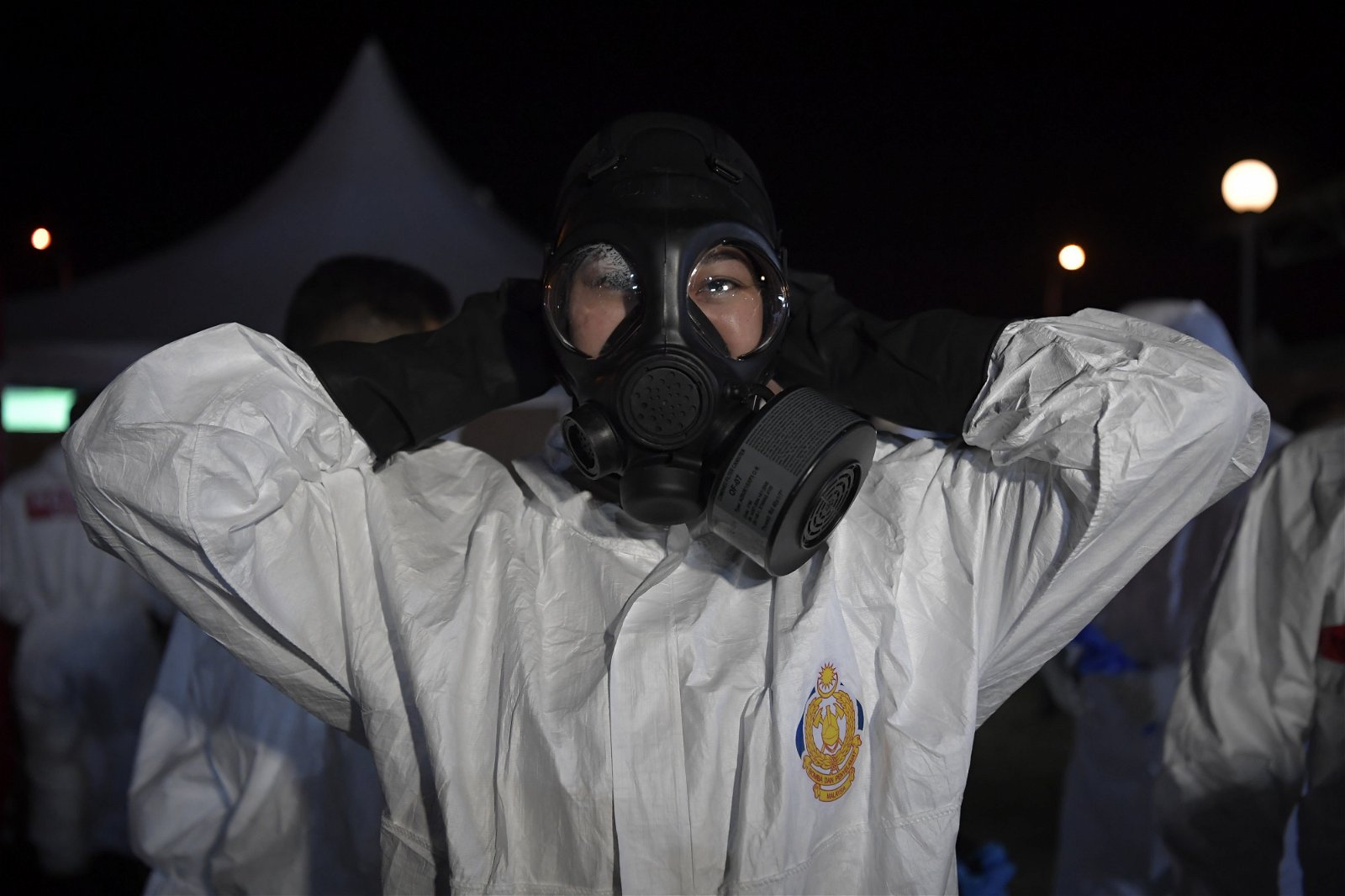 一名危险化学物品处理队（HAZMAT）的女队员投入前线工作前，将个人防护设备（PPE）穿戴好。