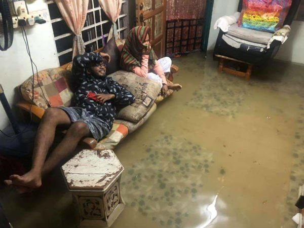 水淹进屋内，居民无奈将双脚搁在沙发上，等待积水退去。