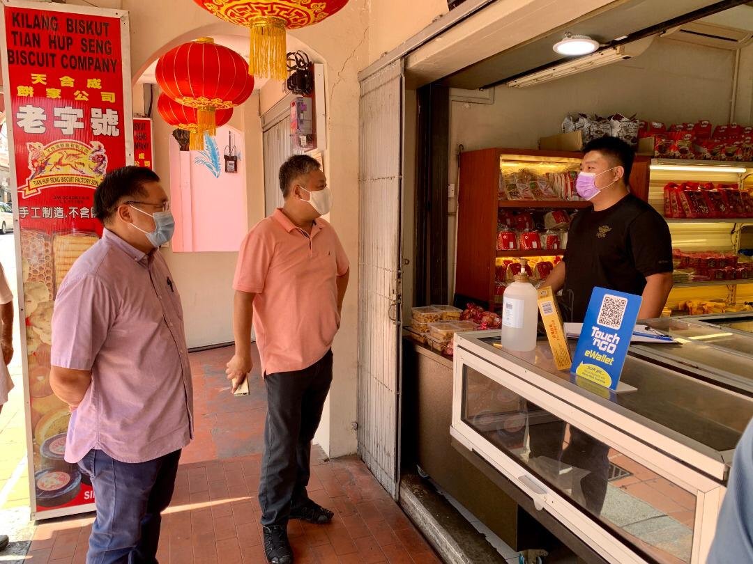 颜天禄（左起）在蔡永泉的陪同下，向鸡场街商家了解店面营业情况。