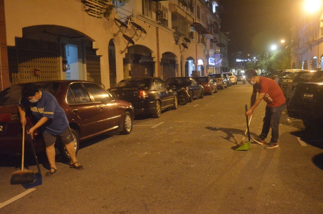 刘志俍（右）与当地居民清理马路上的玻璃碎片。