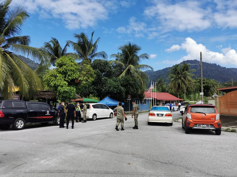军警人员周四在往怡保美露2C花园的主入口，探讨如何实施加强行管令。
