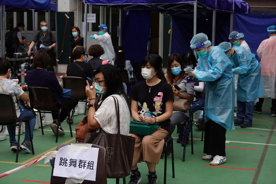 无数名身穿防护服的检测人员于周二，在香港油尖旺区检测中心，为前来的民众进行检测，其中他们都涉及当地名为“跳舞群组”的感染群组。（图取自路透社）