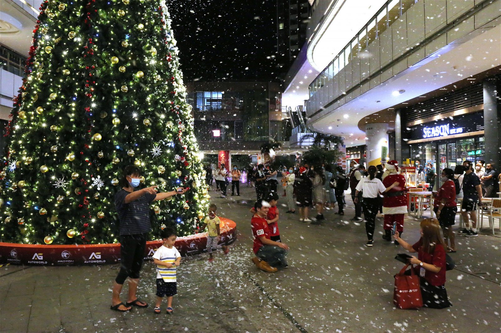从圣诞树顶端落下的皑皑白雪让孩子们乐开怀，一家大小一同感受浓浓的圣诞佳节气氛。（摄影：刘维杰）