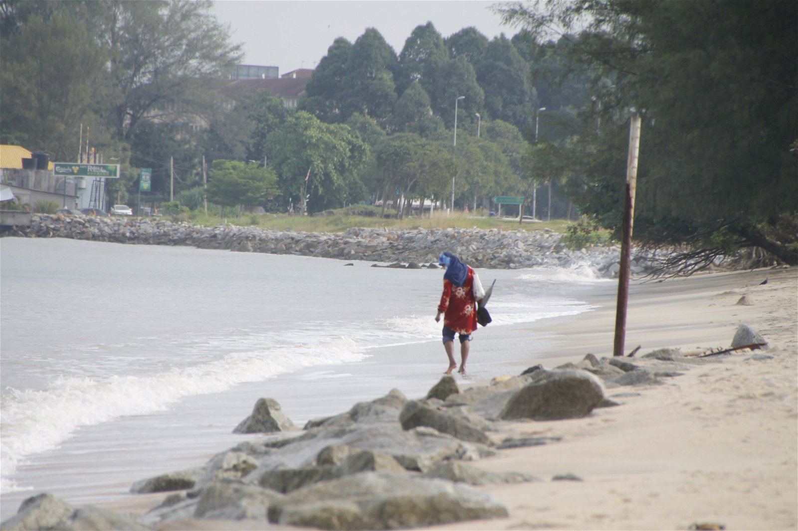 一名巫裔妇女在海边捉蚌，并不知道这里已被封锁。