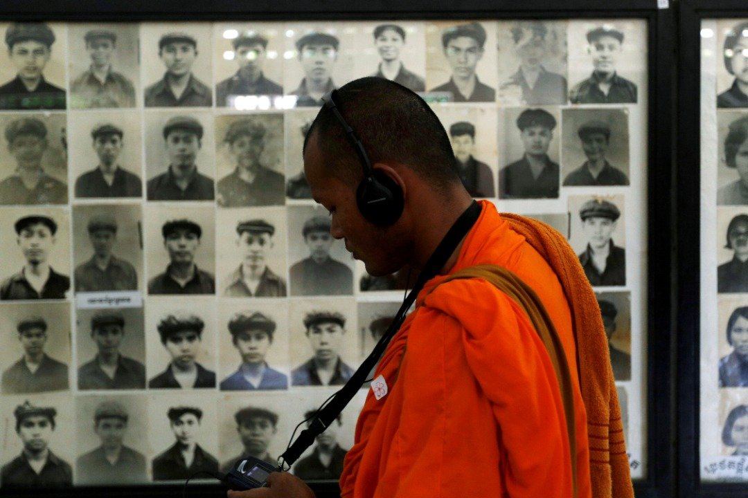 在红色高棉执政期间，累积超过1万4000多人被关押在S-21监狱，囚犯最后幸存者根据记录只有10多人。与集中营如出一辙的S-21监狱，成为红色高棉最令人发指的人间炼狱。这是一名僧人在后来改名的吐斯廉屠杀博物馆观看受害者的照片。（图取自路透社）